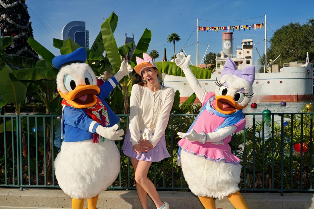 owner of wishes planning services with donald and daisy duck in front of a disney cruise ship